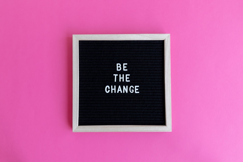Letterboard with 'Be the Change' on a vibrant pink background.